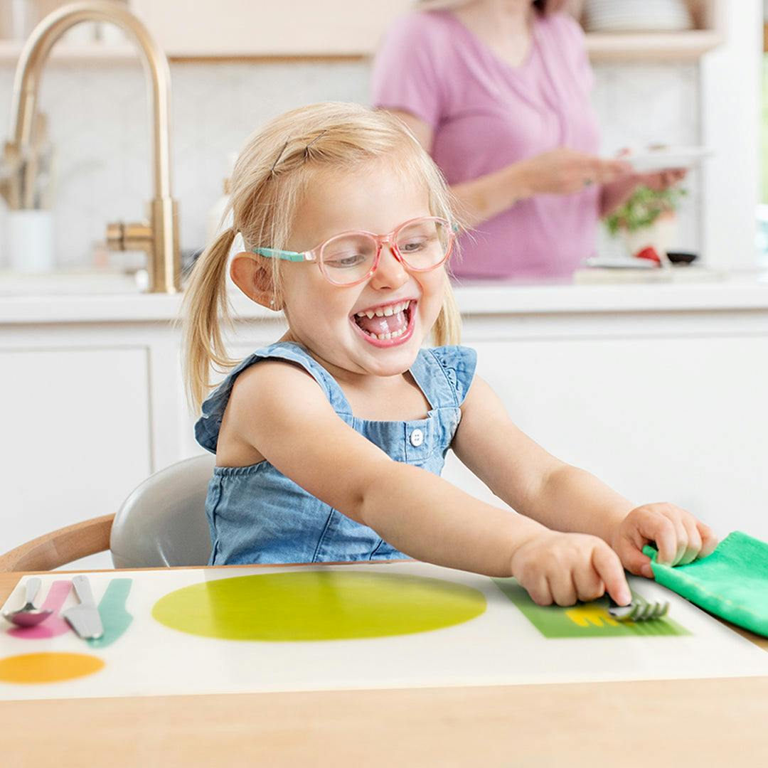 Child using the Montessori Placemat & Utensils by Lovevery